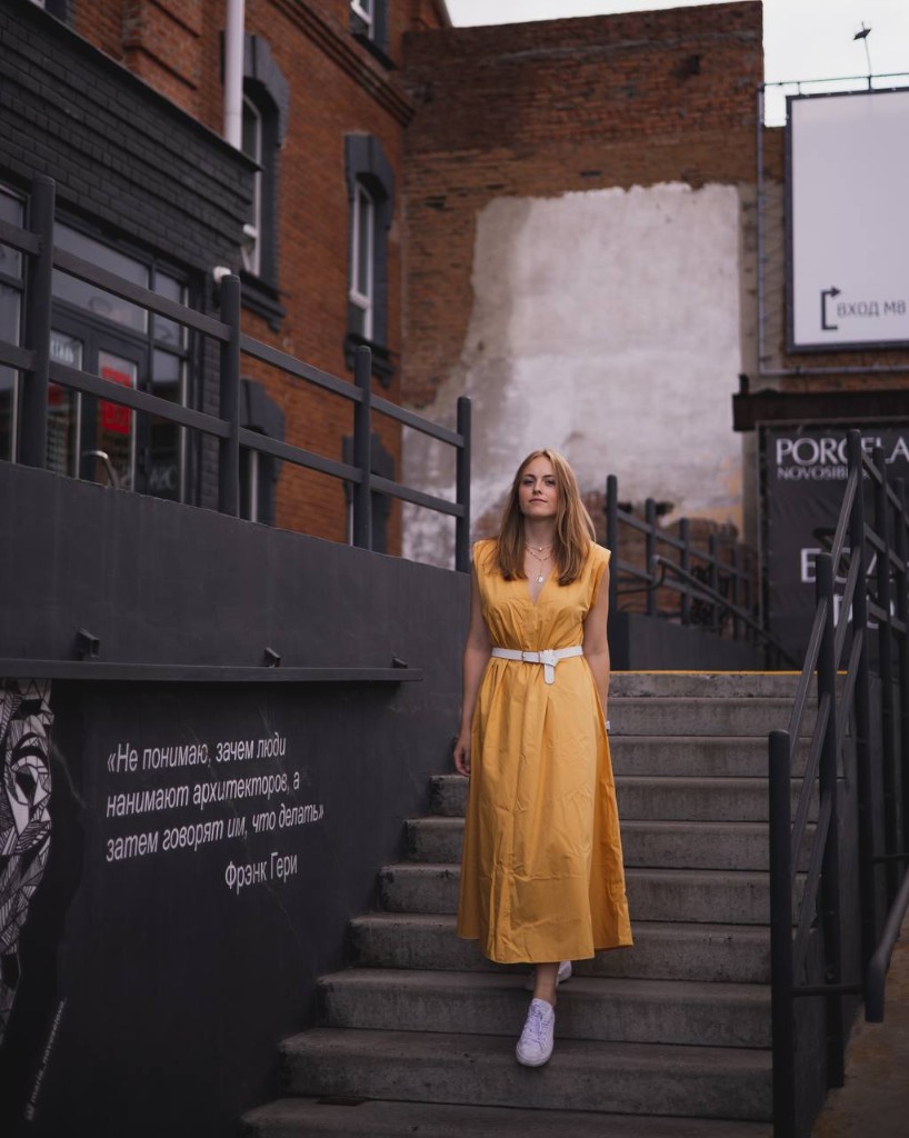 Анастасия Матвеева на фоне городской архитектуры и цитаты Фрэнка Гери в Новосибирске